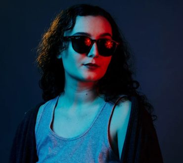 Studio portrait of a woman in sunglasses under red and blue gel lighting
