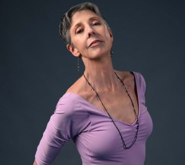 Studio portrait of a female dancer in a lavender top against a dark gray background